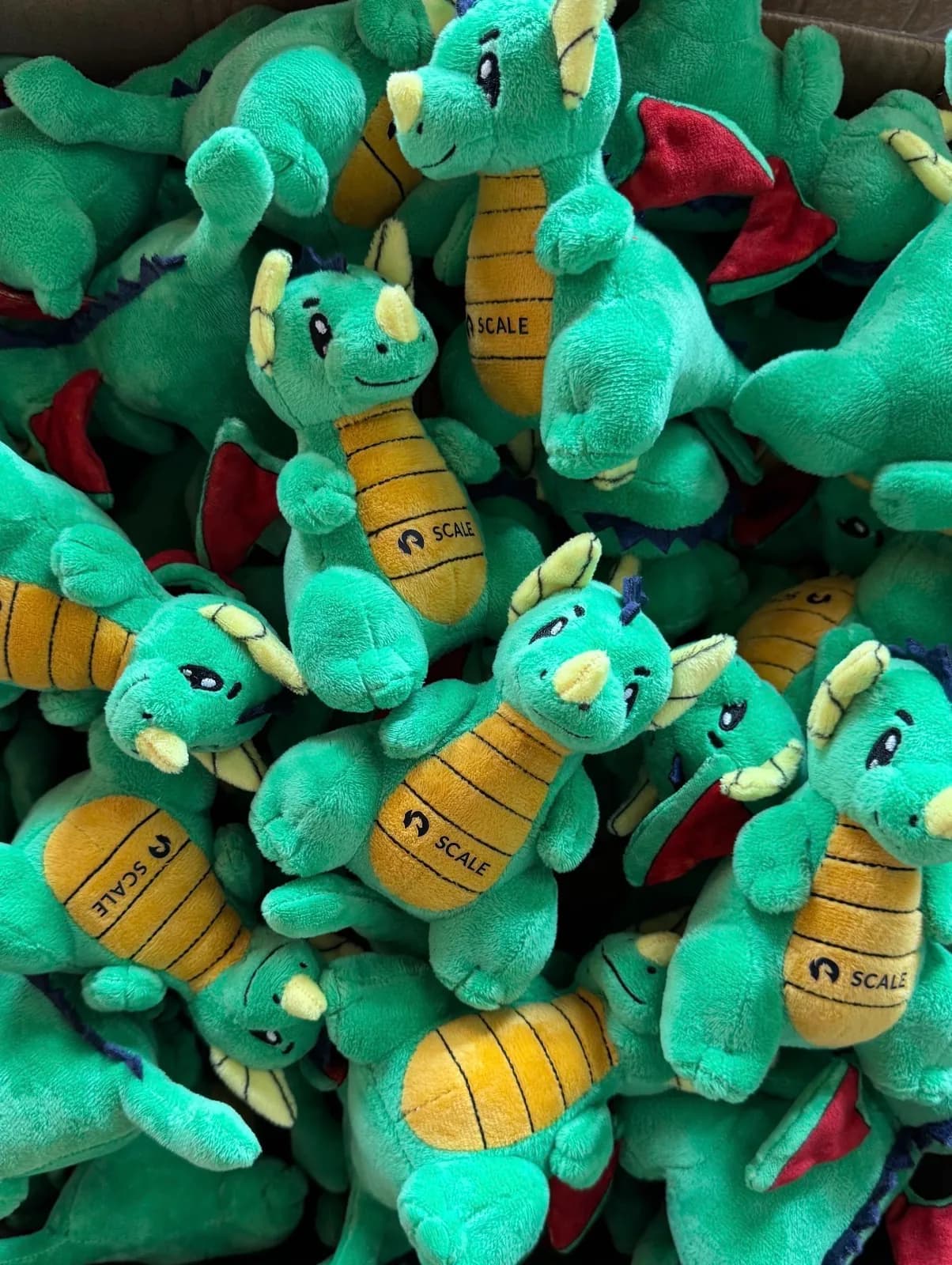 Bulk run of green dragon plush toys held in a hand