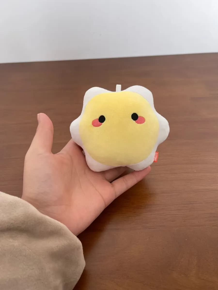 Small yellow flower-shaped plush toy held in a hand