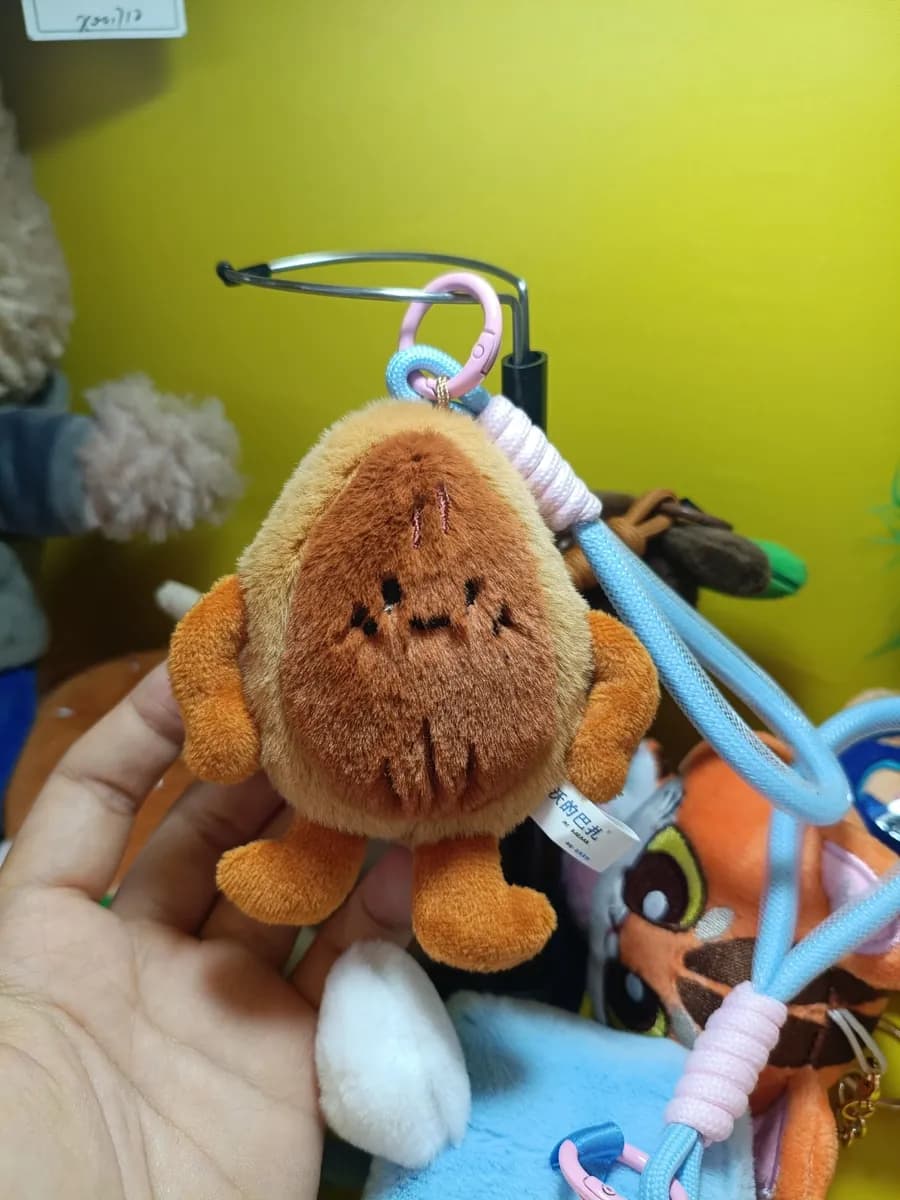 Brown monkey plush charm clipped to a carabiner strap