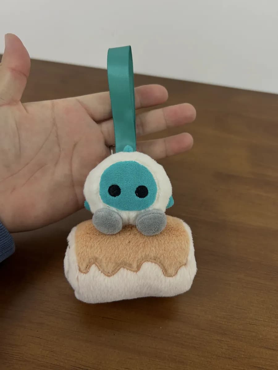 Blue pudding plush keychain on a ribbon strap