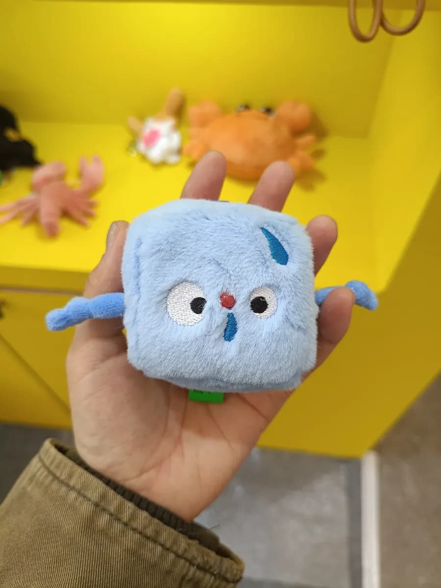 Square plush charm with a printed logo panel
