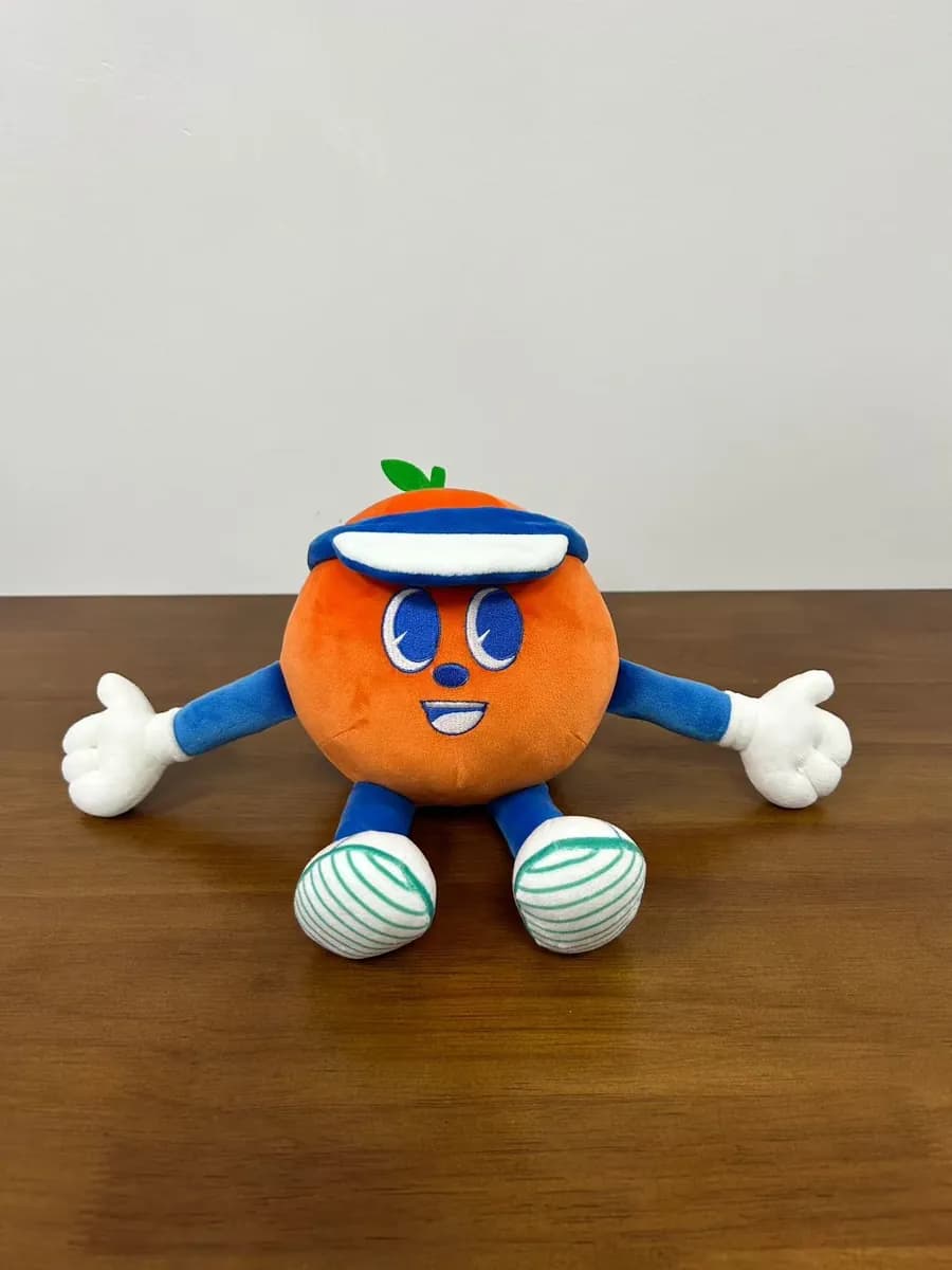 Orange character mascot plush with a printed headband